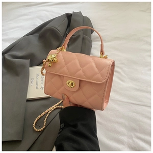 Detail shot of a pink quilted mini bag with gold bear charm and leather chain strap