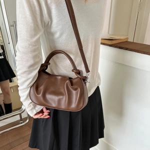 Detail of dark brown ruched cloud bag with leather texture and silver metal hooks