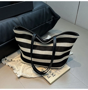 Detail of black and white striped woven tote bag with leather straps and clear texture