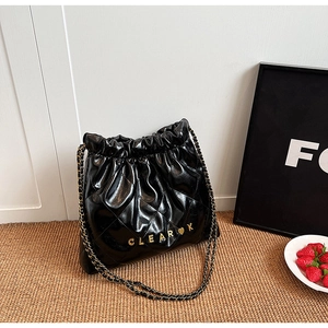 Detail of black quilted bucket bag featuring gold chain strap and logo lettering