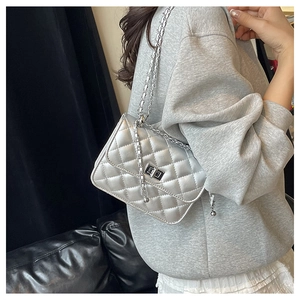 Macro detail of silver quilted chain bag with metallic finish and square twist lock