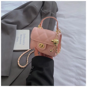 Detail of a pink quilted mini bag featuring a gold ball chain and turn-lock closure