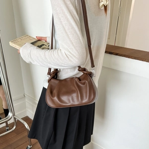 Detail showing the brown pleated cloud bag texture and silver metal strap buckle