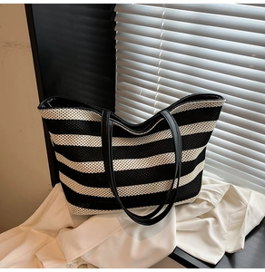Macro shot of minimalist black and white striped woven tote bag with smooth faux leather strap