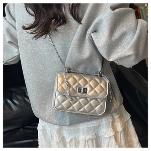 Close-up of silver quilted crossbody bag with metal chain strap and twist-lock