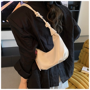 Detalle del bolso hobo de cuero crema con correa de nudos y textura plisada