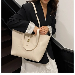 Detailed view of beige pebbled leather tote bag with elegant gold buckle and shoulder strap