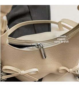 Detail of silver metal zipper on cream-white pleated handbag with smooth closure