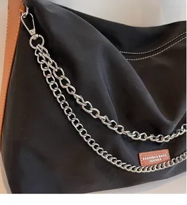 Close-up of nylon tote showing silver chain strap and leather logo patch detail