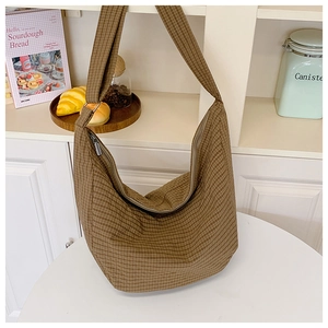 Nahaufnahme der braun karierten Nylon-Tasche mit silbernem Reißverschluss auf weißem Tisch