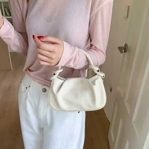 Detail of creamy white pleated cloud bag with a unique knot handle design