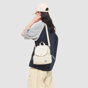 Modèle portant un mini sac à dos en nylon imperméable crème avec sangle réglable