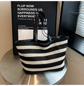 Close-up of black and white striped woven mesh tote bag on minimalist display