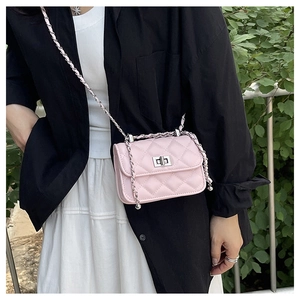 Detail of pink quilted crossbody bag with silver chain strap worn by a model outdoors