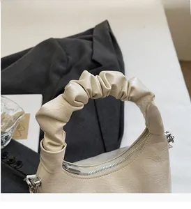 Detail of cream pleated handbag with ruched handle and silver zipper on artistic background