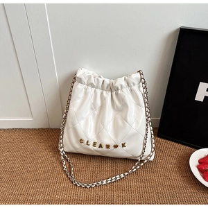 Detail of white quilted bucket bag featuring a gold chain strap and metal letter logo