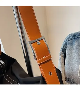 Detail of adjustable brown leather shoulder strap with silver buckle on canvas bag
