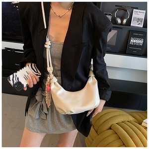 Detalle de bolso medialuna blanco crema con asa anudada y colgante de corazón rosa