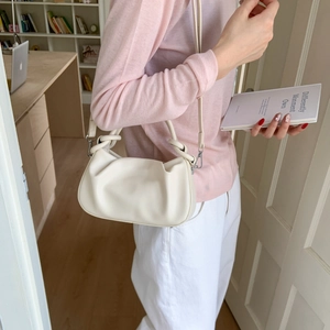 White pleated cloud bag detail with knotted handle and adjustable strap on a model