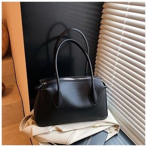 Dettaglio borsa tote nera in pelle martellata con zip argento su un blazer beige