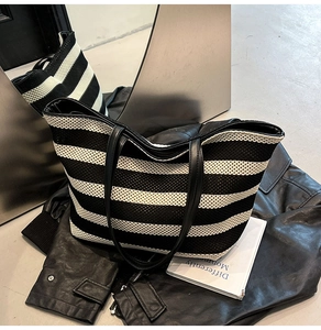 Detail of black and white striped tote bag showing woven texture and leather handle