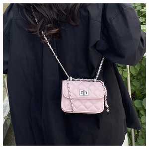 Detail of pink quilted crossbody bag with silver twist lock and woven metal chain strap