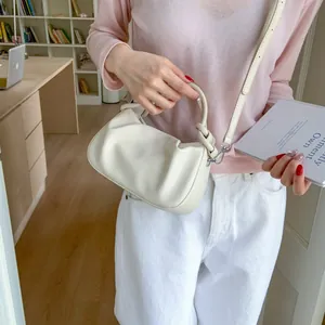 Detailed view of cream pleated cloud bag with soft leather knot handle and shoulder strap