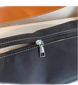 Detailed close-up of smooth silver metal zipper and white contrast stitching on nylon bag