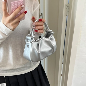 Detail of silver metallic pleated cloud bag featuring unique knotted handle and hook