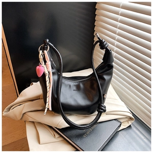 Detalle de bolso hobo negro con correa de nudo y colgante de corazón rosa moderno