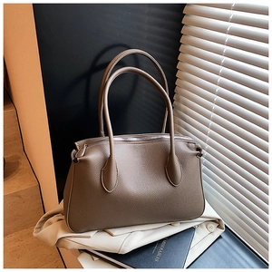 Borsa tote marrone scuro con trama litchi su un blazer con luce naturale della finestra