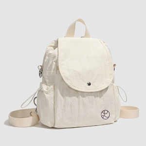 Détail du sac à dos en nylon crème avec poches latérales à cordon et boucle métallique