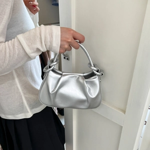 Detail of silver pleated cloud bag with metallic finish and twisted handle design
