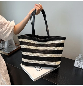 Close-up of black and white striped woven tote bag with leather handle and metal zipper