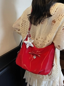 Chic red patent leather crescent shoulder bag with metallic heart charm and bow details