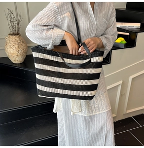 Detail of striped woven tote bag featuring black leather straps and mesh texture
