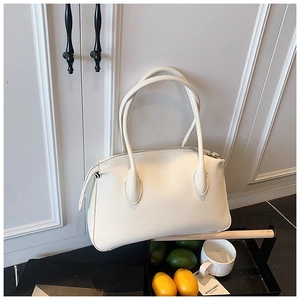 Borsa a mano in pelle bianca con grana litchi e zip argentata su un vassoio