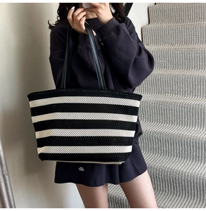 Detail of black and white striped knit tote bag with durable faux leather shoulder strap