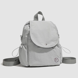 Détail d'un sac à dos en nylon gris clair avec rabat à pression et bretelles réglables