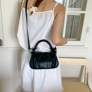 Detail of black pleated cloud bag with thick handle and detachable shoulder strap