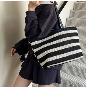 Detailed view of striped woven tote bag with durable black shoulder strap and soft texture