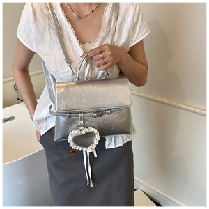 Detail of silver pleated leather backpack with lace heart charm and metallic finish
