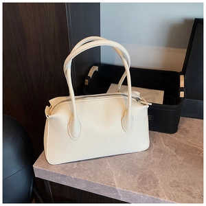 Dettaglio della trama in pelle martellata e cerniera in metallo sulla borsa beige
