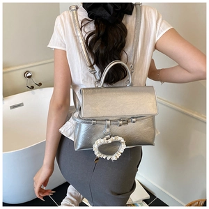 Detail of silver metallic convertible backpack with heart charm and lace trim