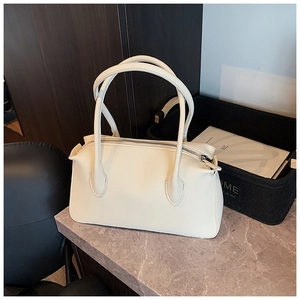 Dettaglio della borsa color crema con trama litchi e doppi manici su base di marmo