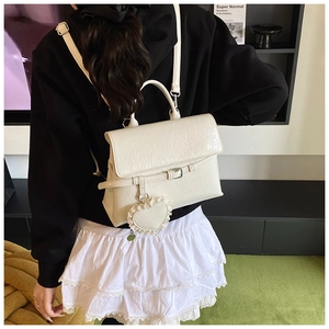 Detailed texture of white vintage pleated leather bag with a heart lace charm pendant