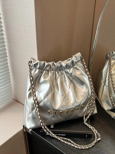 Quilted silver drawstring bucket bag with metallic finish and gold metal chain strap
