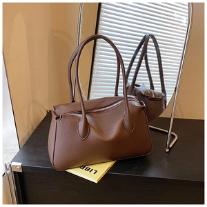 Dettaglio della borsa a spalla in pelle marrone scuro con trama a grana e zip in metallo