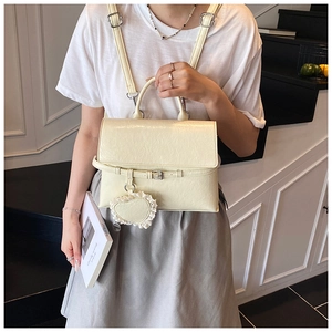 Close-up of cream PU leather convertible backpack with heart charm in a lifestyle setting