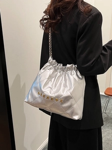 Chic silver quilted bucket bag with chain strap and metal letter logo shown on model
